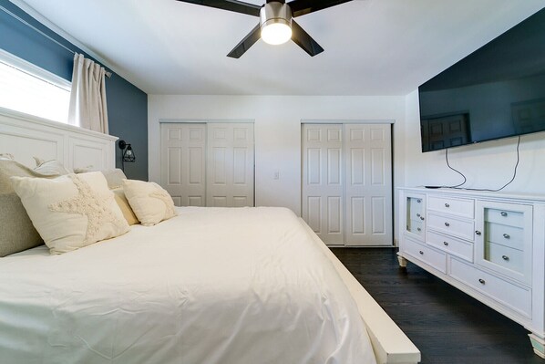 A bedroom with a bed, white dresser, and a ceiling fan. - Work & Unwind in North Port Fenced Yard + Cozy Lounge (North Port)