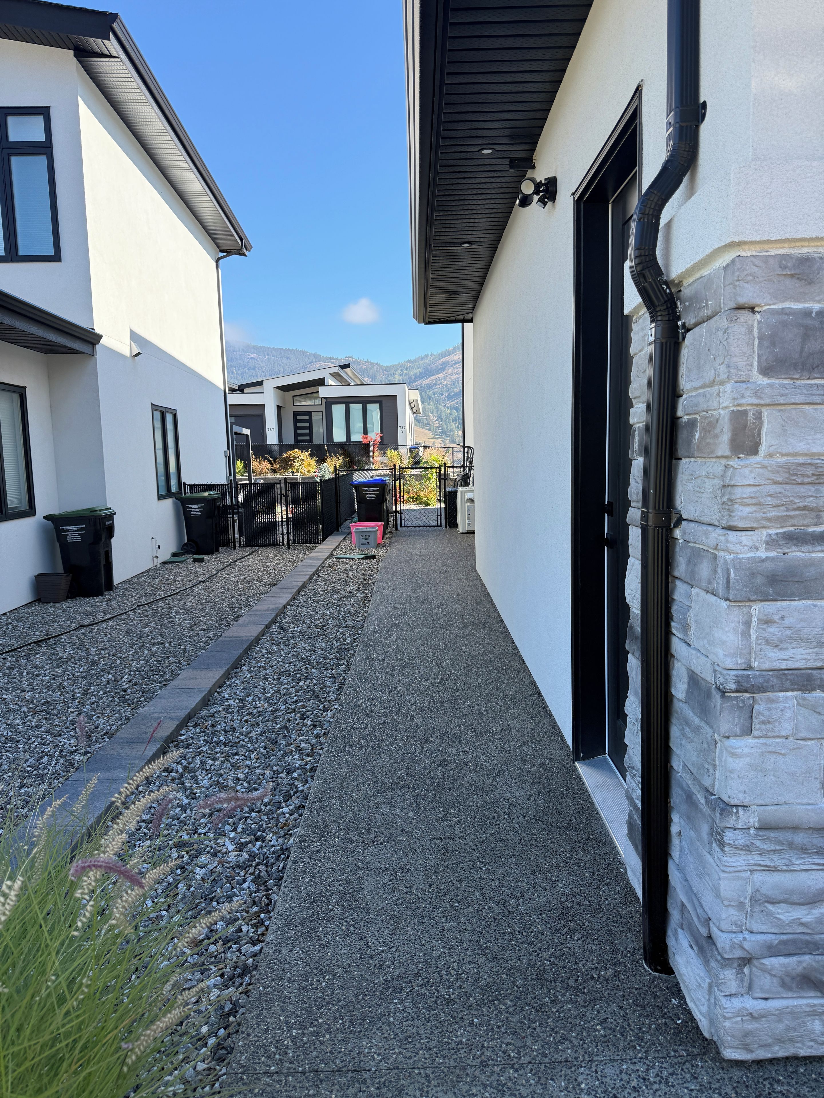 A pathway leading to a building with a stone facade and a black door.