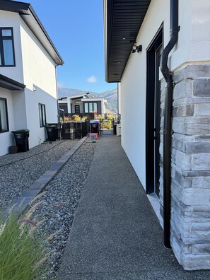 A pathway leading to a building with a stone facade and a black door.