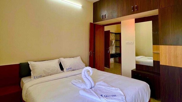 Camera d'albergo con un letto, un armadio, uno specchio e una ventola a soffitto.