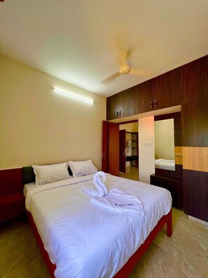 Una habitación de hotel con cama, armario, espejo y ventilador de techo.