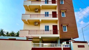 Un edificio residenziale a più piani con balconi, un ingresso con cancello e un cartello che indica proprietà J.K. Homes.