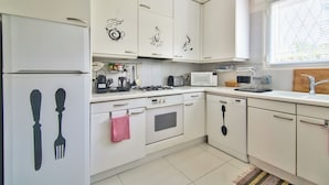 Une cuisine avec des meubles blancs, un four à micro-ondes, une cuisinière et un lave-vaisselle.