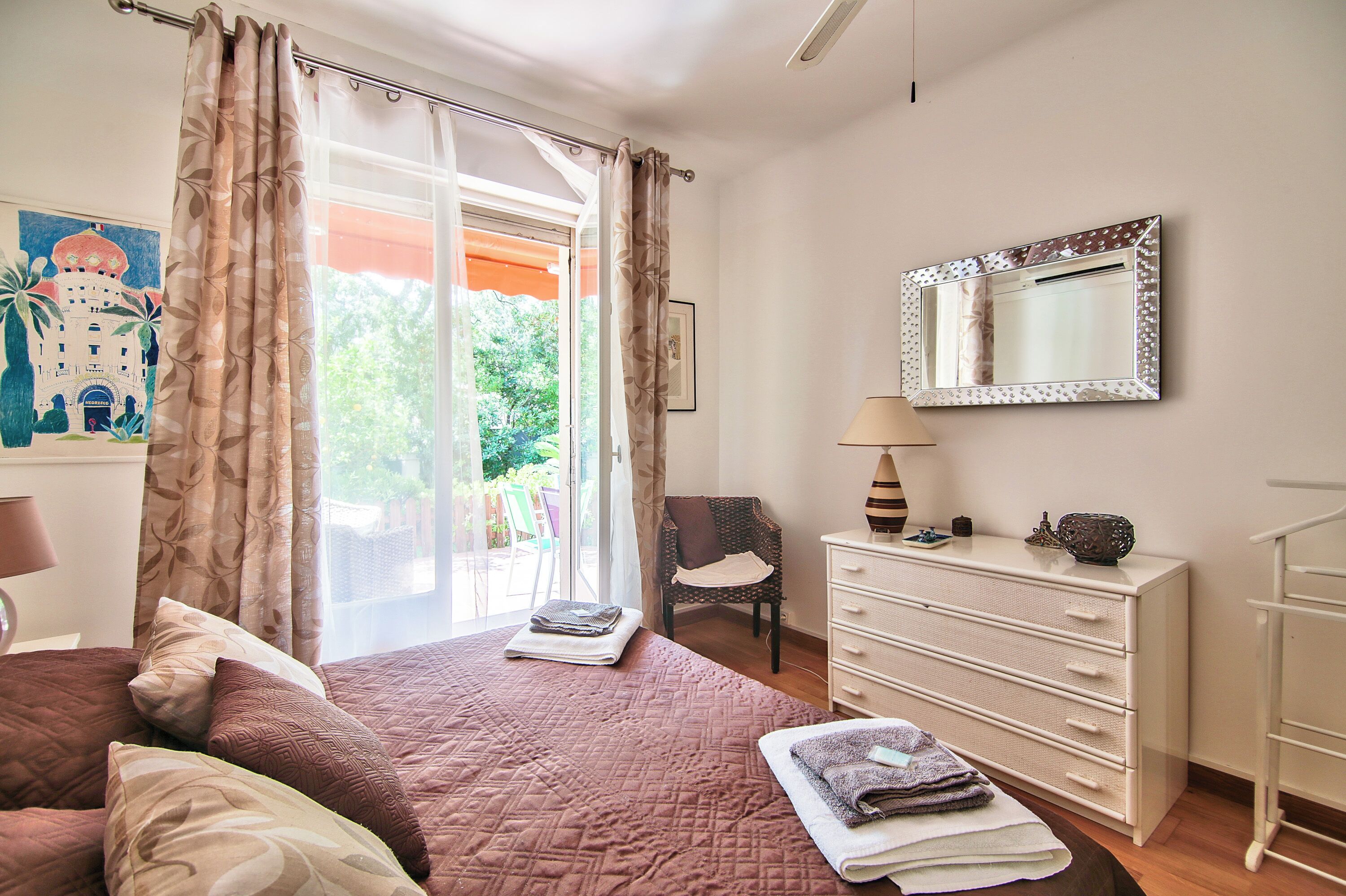 A bedroom with a bed, a dresser, a chair, a mirror, and a window with curtains.