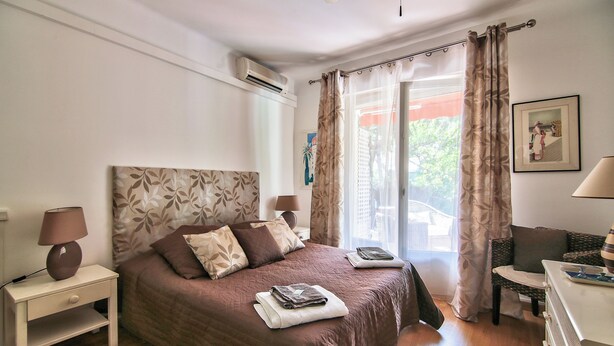 Une chambre à coucher bien rangée, avec un lit, des lampes de chevet, une table de chevet, une chaise et un bureau.