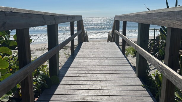 Un muelle de madera que lleva a una playa con vistas al océano.