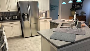 Una cocina moderna con un refrigerador de acero inoxidable, un lavavajillas empotrado y una encimera de granito.