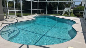 Una piscina azul cristalina con borde de azulejos, rodeada por un porche cubierto.