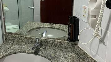 A bathroom with a granite countertop sink, a mirror, a wooden door, and a telephone.