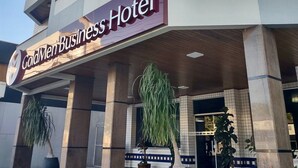 The exterior of the GoldMen Business Hotel with a modern facade, large potted plants, and a clear sky. - Goldmen Business Criciúma (Criciuma)