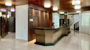 A reception area with a marble counter, wooden paneling, and a tiled floor. - Goldmen Business Criciúma (Criciuma)