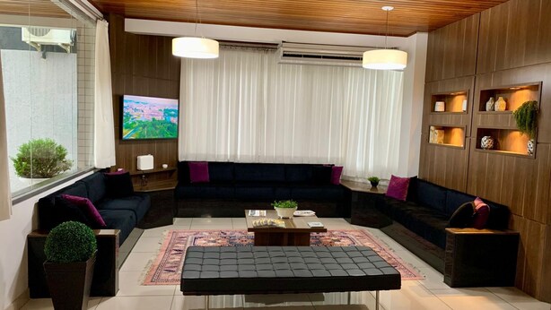 A modern living room with a sectional sofa, a coffee table, and a TV mounted on the wall. - Goldmen Business Criciúma (Criciuma)