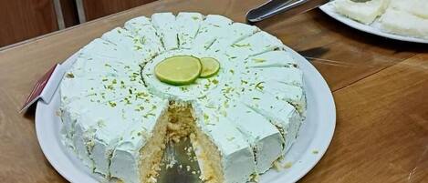 A round cake with lime slices on top, placed on a white plate with a serving spoon.