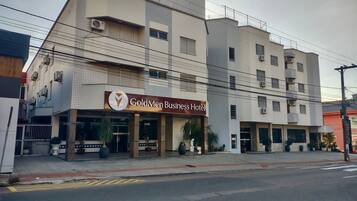 Un hotel llamado GoldMen Business Hotel con una fachada moderna, varios pisos y una entrada destacada con un letrero.