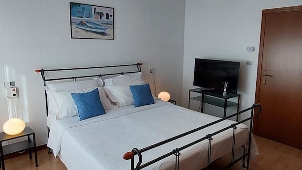 A bedroom with a bed, a ceiling fan, a TV, and a door. - Casa Pisani - Two Bedroom Apartment, Sleeps 6 (Rimini)