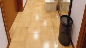 A hallway with wooden doors, a tiled floor, a black trash bin, and a mirror with a black frame. - Casa Pisani - Two Bedroom Apartment, Sleeps 6 (Rimini)