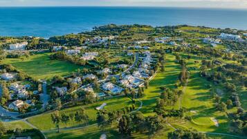 Vista aérea de una zona residencial costera con casas, áreas verdes y un campo de golf.