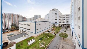 Ένα σύγχρονο κτίριο κατοικιών με επίπεδη στέγη, πολλά μπαλκόνια και μια κεντρική αυλή με πράσινο.