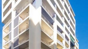 A multi-story building with balconies, a parking area with cars, and a clear sky. - Faia Praia da Rocha Pool Terrace Flat (Portimão)