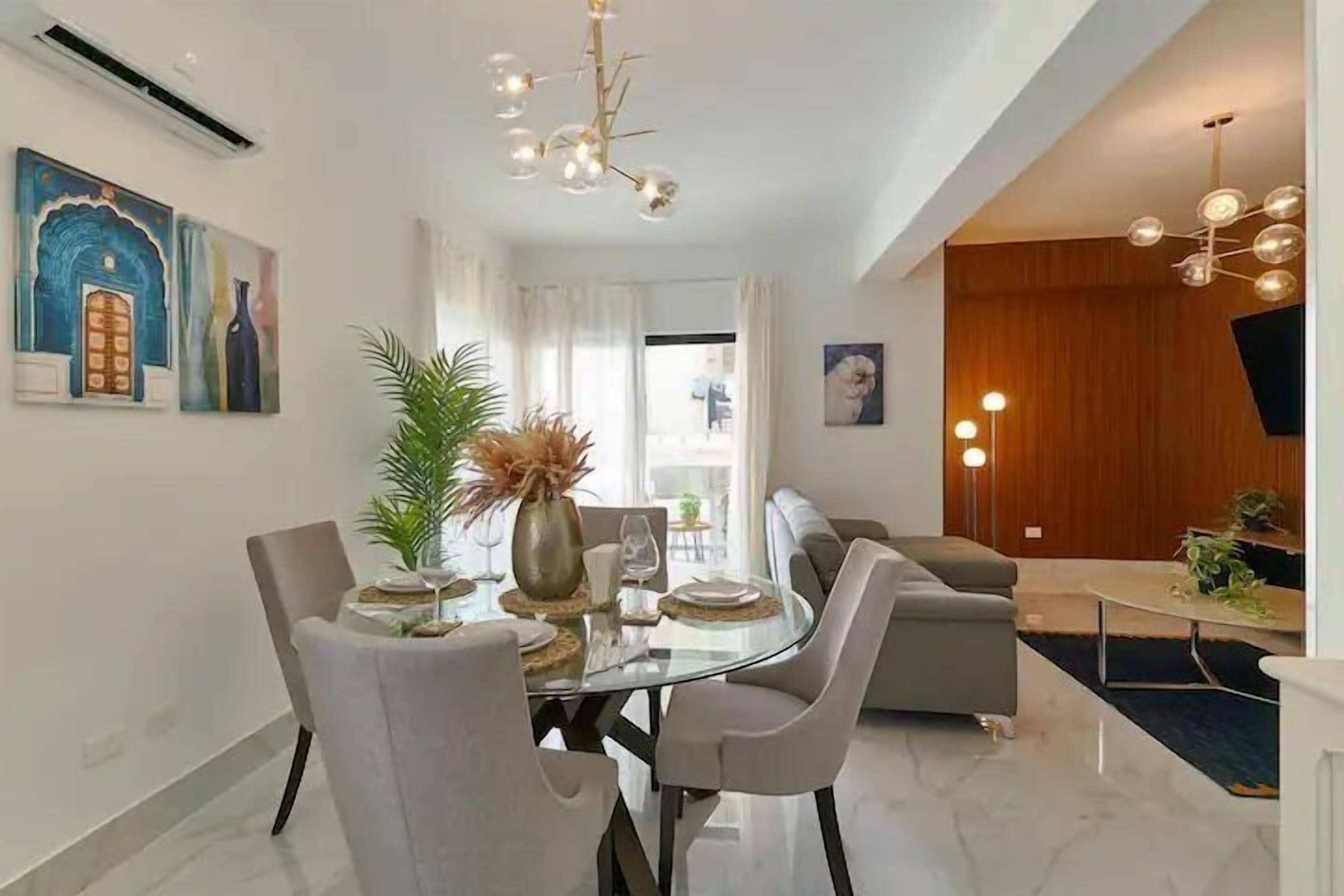 Una sala moderna con una mesa de comedor de vidrio, sofás grises y una pared de acento de madera.