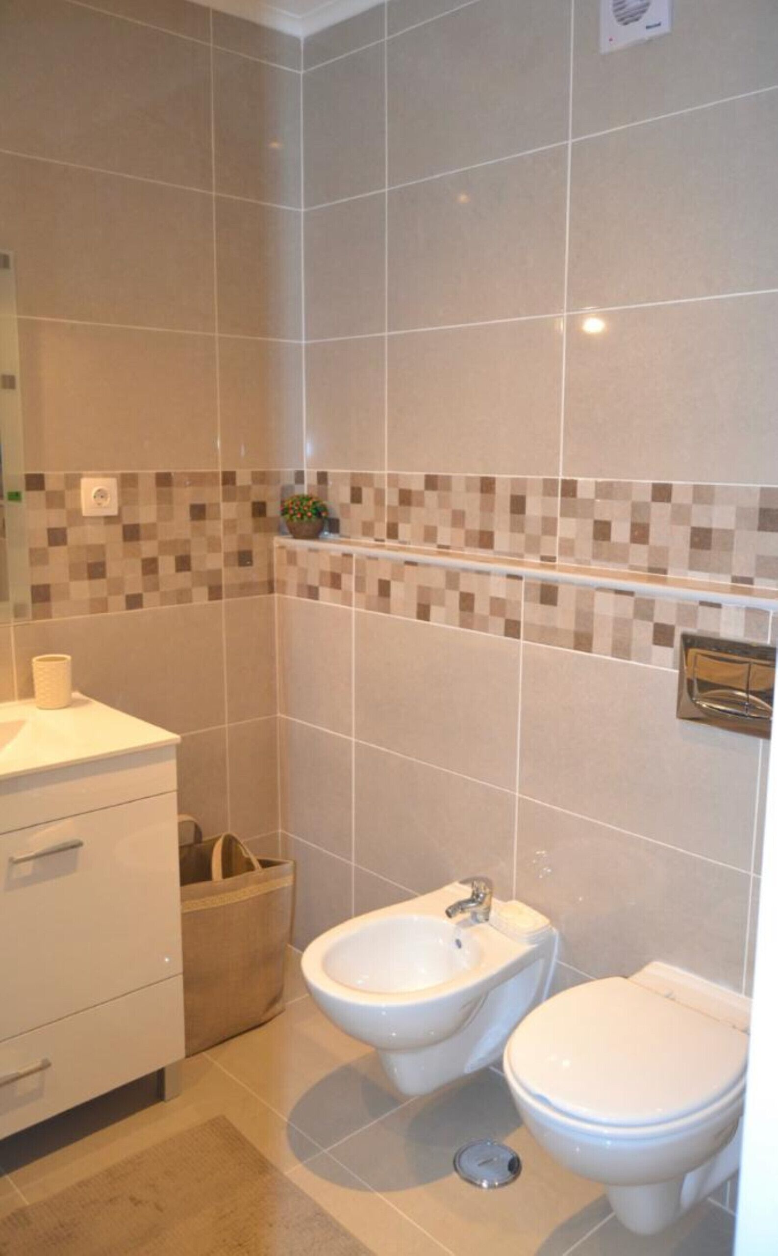 A bathroom with a toilet, bidet, and a sink.