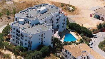 Un hotel de varios pisos con piscina en la azotea y jardín ajardinado.
