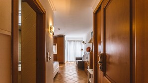 A hallway with a bed, a desk, and a cabinet.