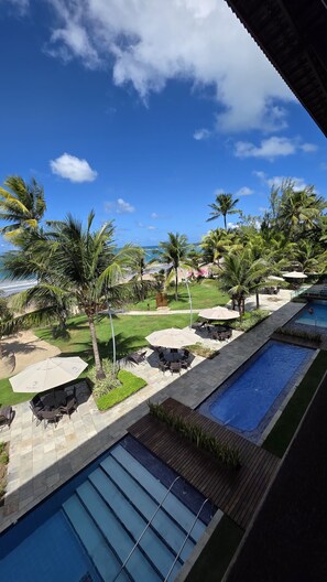 A resort pool area with multiple pools, palm trees, and outdoor seating. - Porto Beach Beira Mar 306 by La Playa (Ipojuca)