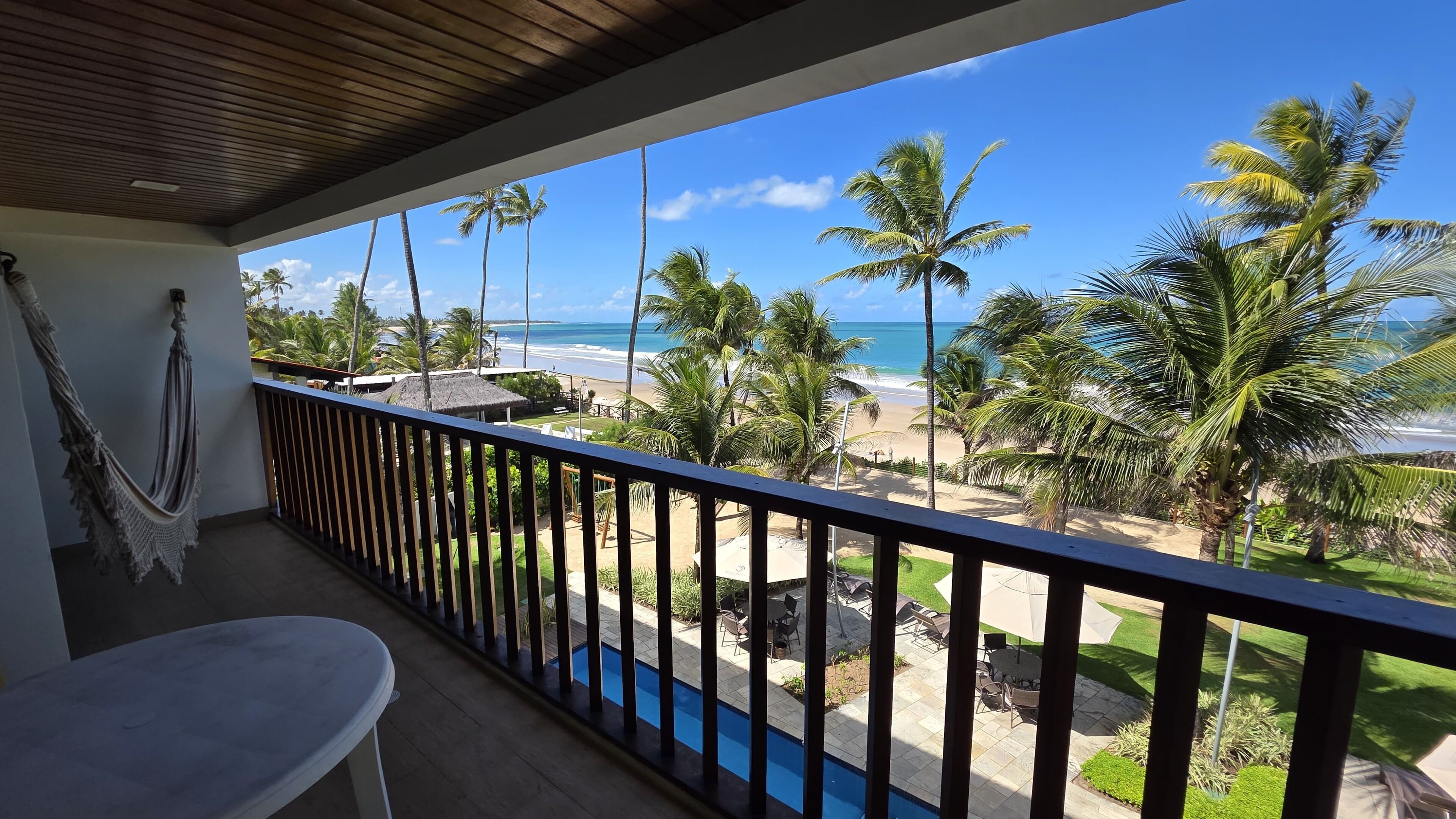 A balcony with a view of a beach and palm trees.