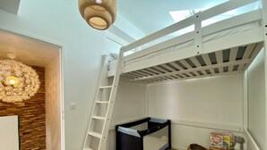 Et soveværelse med køjeseng, en lille skrivebord og en reol med bøger og legetøj.
