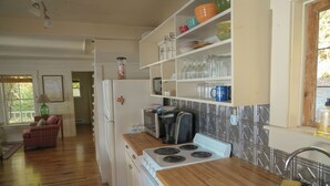 Une cuisine avec des plans de travail en bois, une cuisinière, un évier et des étagères remplies d’assiettes et de bocaux.