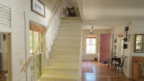 Un escalier menant à un deuxième étage, au-dessus duquel est accrochée une pancarte encadrée portant le mot « famille ».