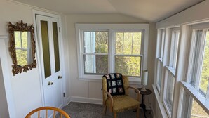 A room with a wooden chair, a door with a mirror, and a window with a view of trees. - Retro Lakeside Charmer in Wonderful Wautoma with WiFi, AC and lake frontage (Wautoma)