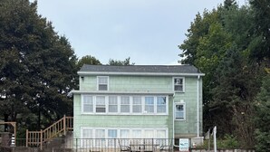 A building with a green exterior, a dock, and a rocky shoreline. - Retro Lakeside Charmer in Wonderful Wautoma with WiFi, AC and lake frontage (Wautoma)