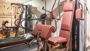Een fitnessruimte met cardioapparatuur, krachttoestellen en een spiegelwand.