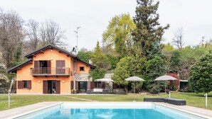 Een huis met een zwembad, tuinmeubilair en een tuin.