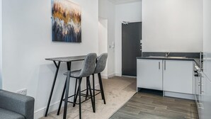 A modern kitchen with white cabinets, a dark countertop, and a painting on the wall. - GuestReady – Modern comfort in Liverpool (Liverpool)