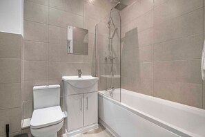 A modern bathroom with a toilet, sink, and bathtub. - GuestReady – Modern comfort in Liverpool (Liverpool)