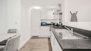 Una cucina moderna con mobili bianchi, un piano di lavoro in granito e un lavello in acciaio inossidabile.