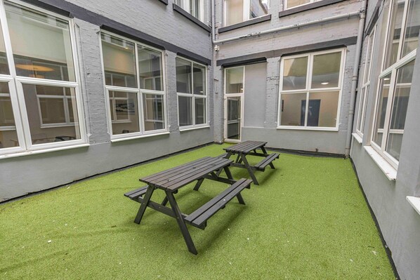 A courtyard with artificial grass and picnic tables.