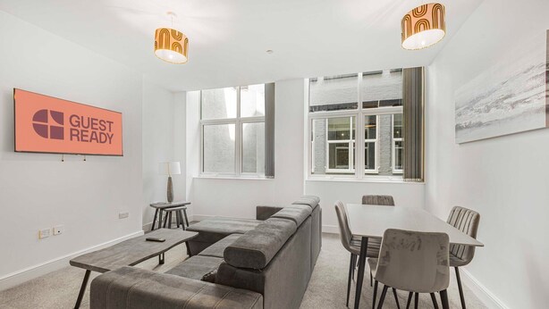 A modern living room with a grey sectional sofa, a dining table with chairs, and two pendant lights. - GuestReady – Relaxing retreat in Liverpool (Liverpool)