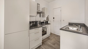 A compact kitchen with white cabinets, a built-in oven, a toaster, and a stainless steel sink. - GuestReady – Stylish and central Liverpool retreat (Liverpool)