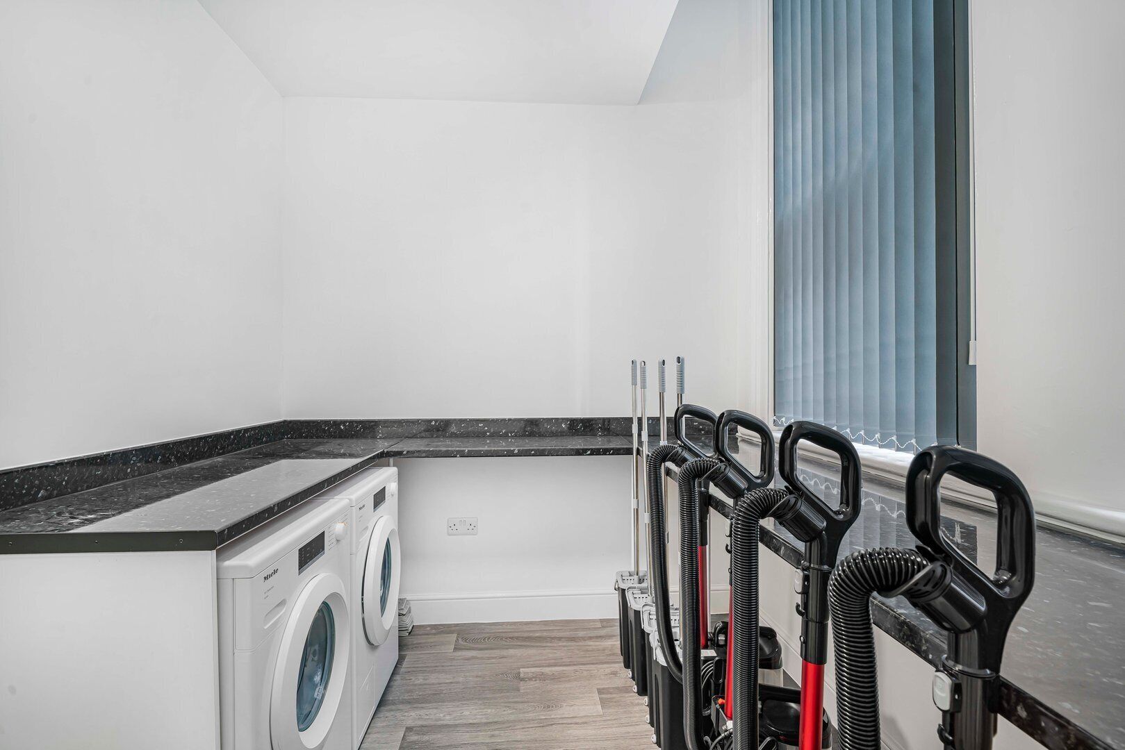A laundry room with a washing machine, dryer, and a hose reel system.