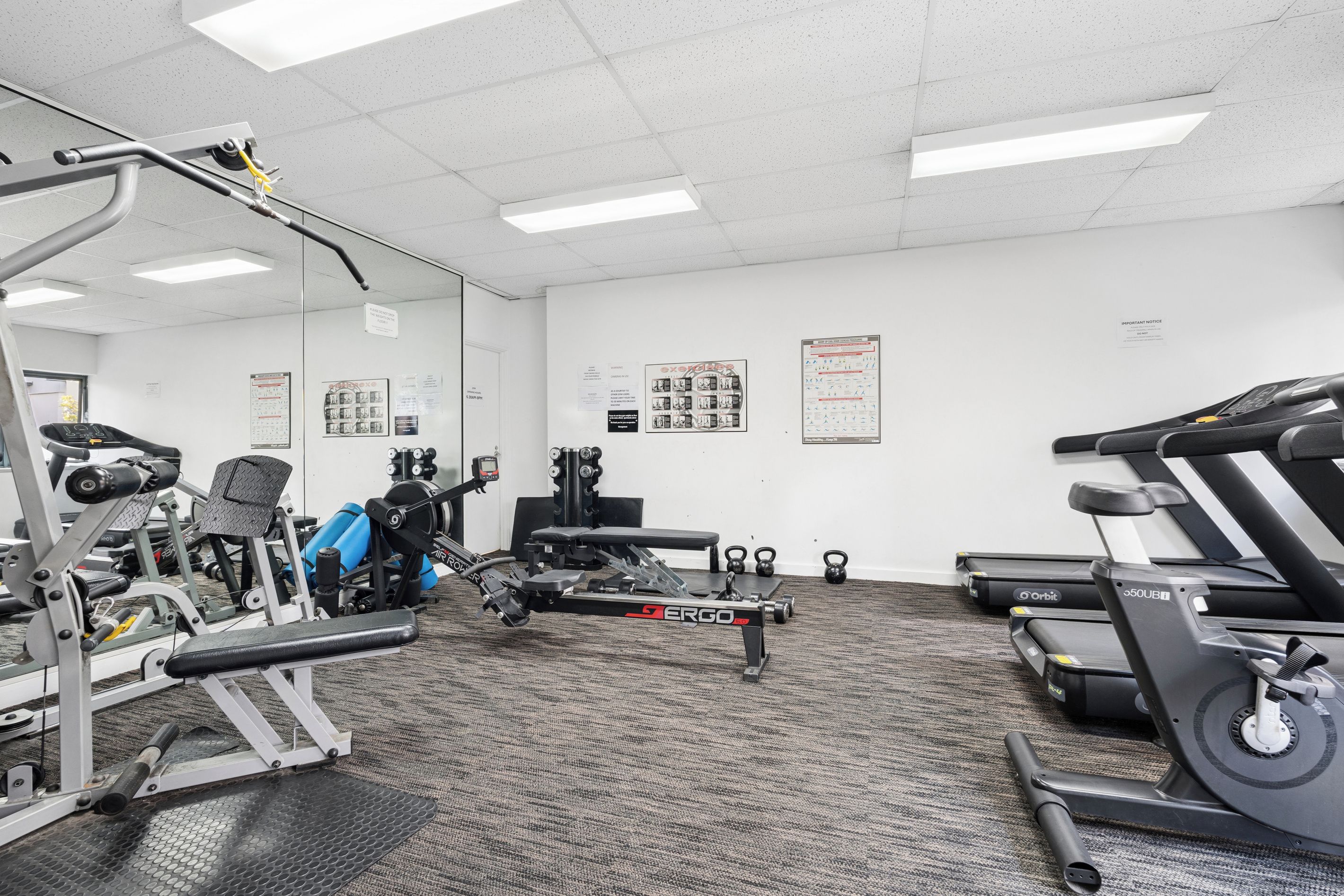 A gym with various exercise equipment, including a treadmill, stationary bikes, and weight machines.