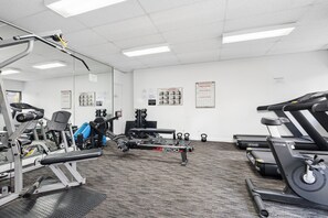 A gym with various exercise equipment, including a treadmill, stationary bikes, and weight machines. - Tulizo  | Walk to Elizabeth Quay • Pool & Parking (Perth)