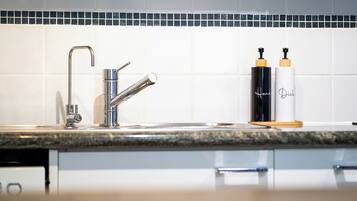 A modern kitchen with a stainless steel faucet, a granite countertop, and two soap dispensers labeled 'Hands Dish.'