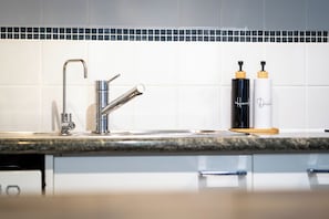A modern kitchen with a stainless steel faucet, a granite countertop, and two soap dispensers labeled 'Hands Dish.' - Tulizo | Elegant 2BR • Perth CBD • Parking (Perth)