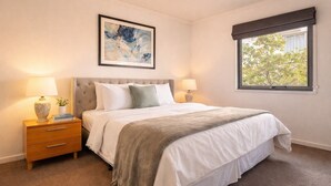 A bedroom with a bed, bedside tables, a window with a view, and a painting on the wall. - Tulizo  | Walk to Elizabeth Quay • Pool & Parking (Perth)