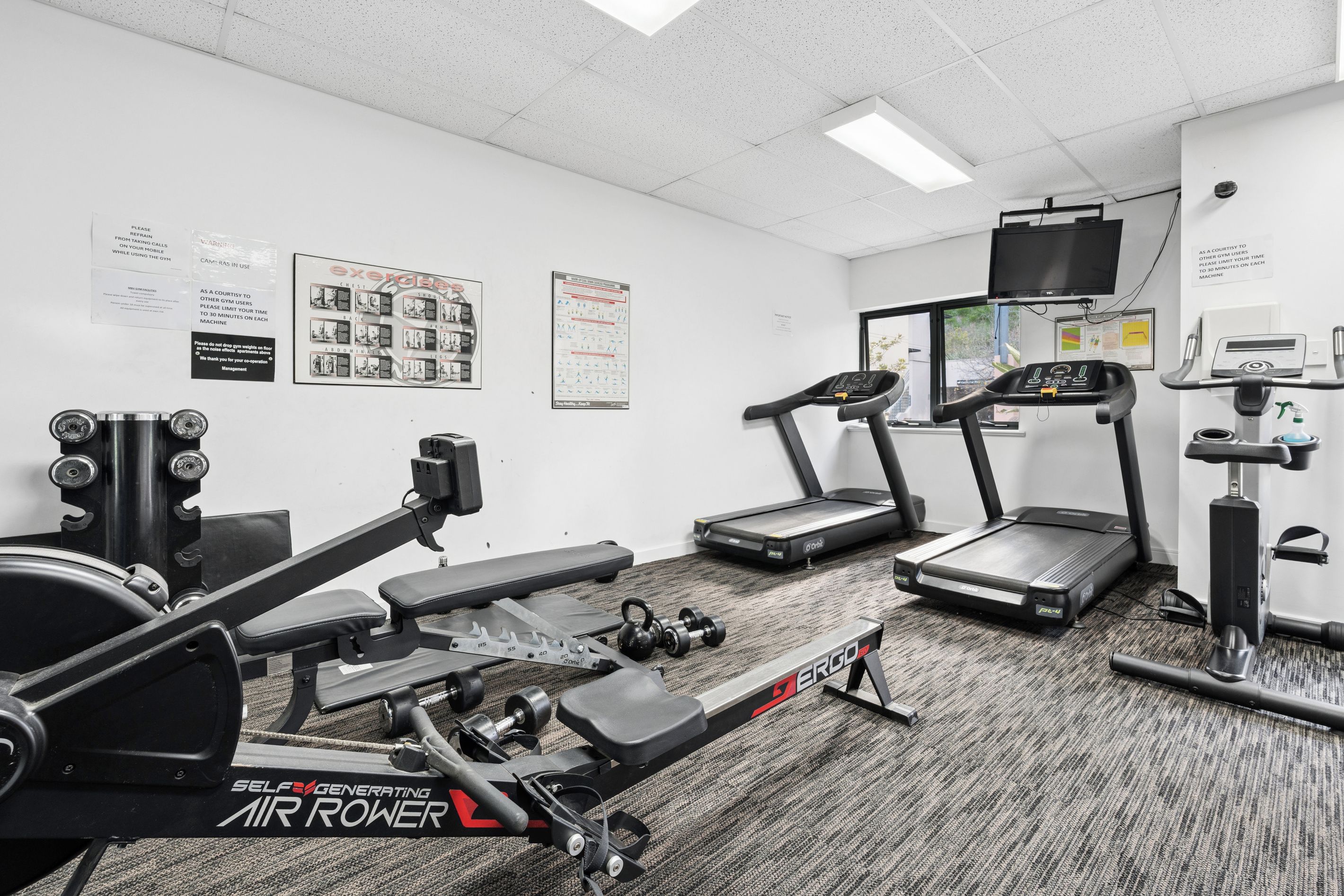 A gym with various exercise equipment including a treadmill, stationary bike, and weight machines.