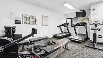 A gym with various exercise equipment including a treadmill, stationary bike, and weight machines.